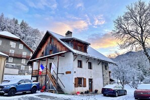 Un chalet traditionnel avec un toit à forte pente, un revêtement extérieur en bois et un drapeau.