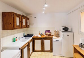 Une cuisine de taille réduite, dotée de meubles de rangement en bois, d’un évier, d’un four à micro-ondes et d’un réfrigérateur.