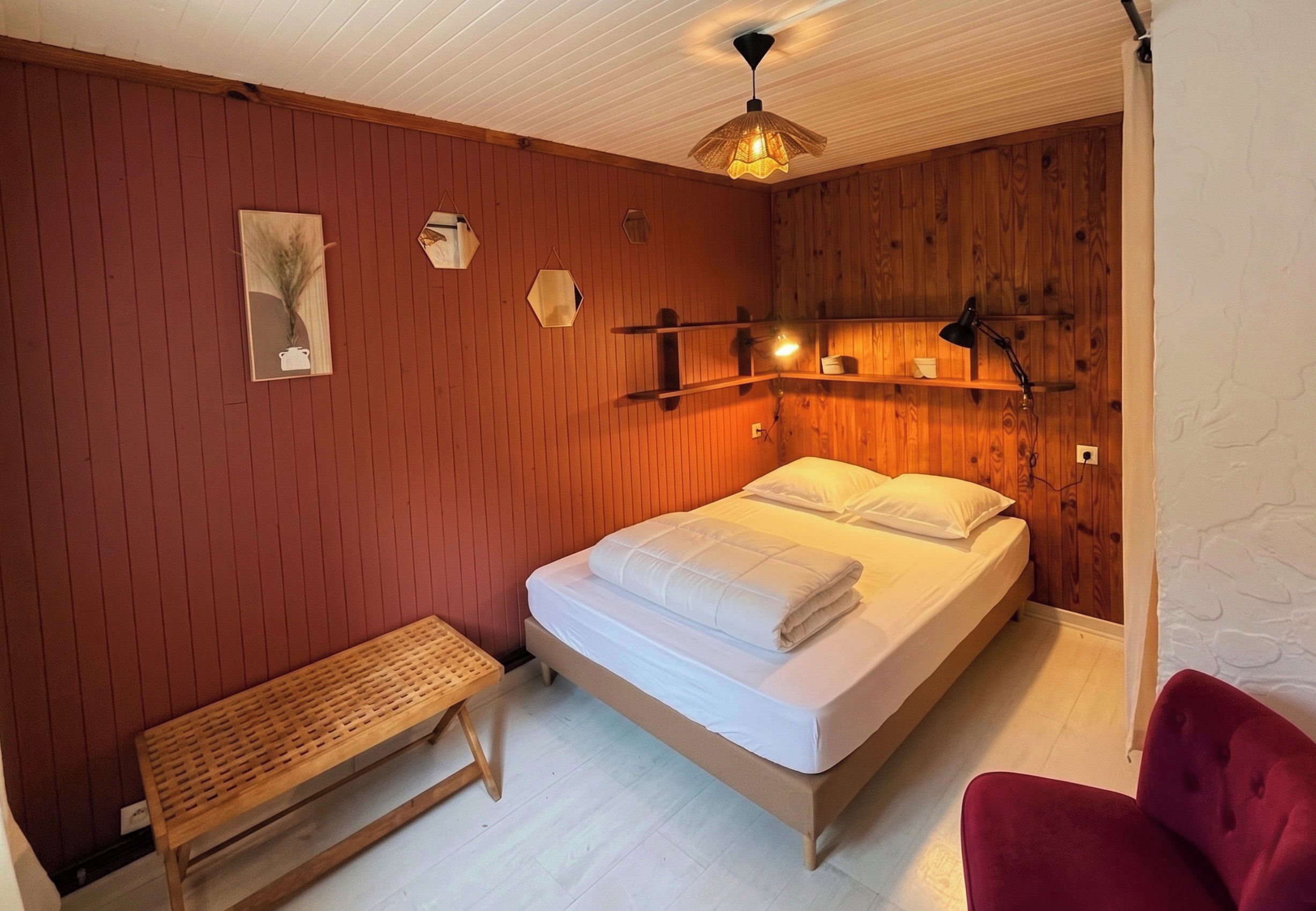 A bedroom with a wooden bed, a bench, and a red chair.
