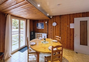 Uma sala de jantar com mesa redonda, cadeiras, um relógio e uma porta.