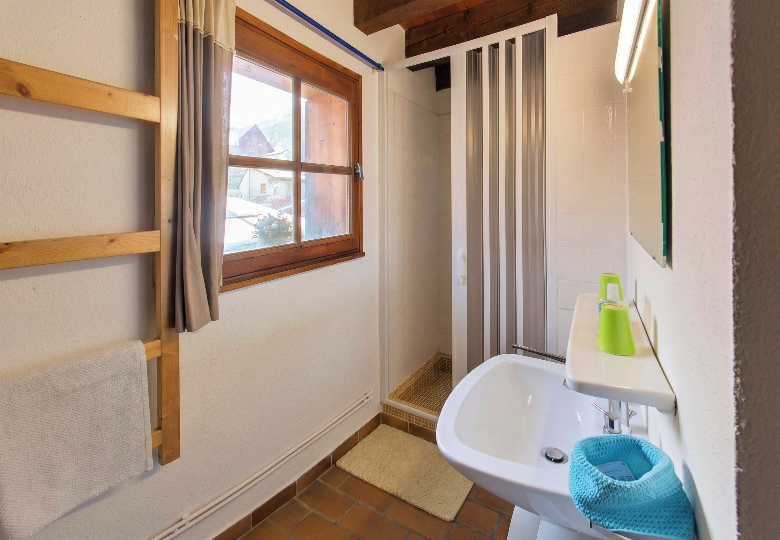 Een badkamer met een raam, een wastafel en een handdoekhouder.