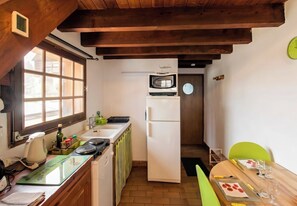 Une cuisine compacte dotée d’une fenêtre, d’un four à micro-ondes, d’un réfrigérateur et d’un coin repas avec une table et des chaises.