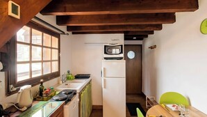 Una cocina compacta con ventana, microondas, refrigerador y comedor con mesa y sillas.