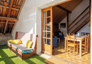 Un interior acogedor con un banco de madera, un sofá con cojines amarillos, una mesa de comedor con sillas y una escalera.