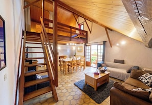 Un loft spacieux avec un escalier en bois, un coin repas et un espace salon confortable.