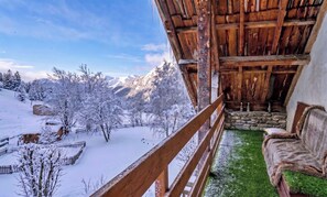 Una cabana de fusta amb un balcó que dona a un paisatge nevós i muntanyes.