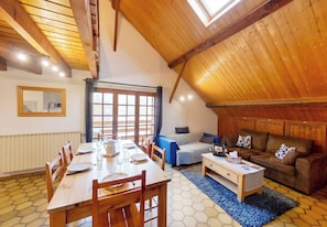 A cozy loft-style room with a dining area, a sofa, and a window.