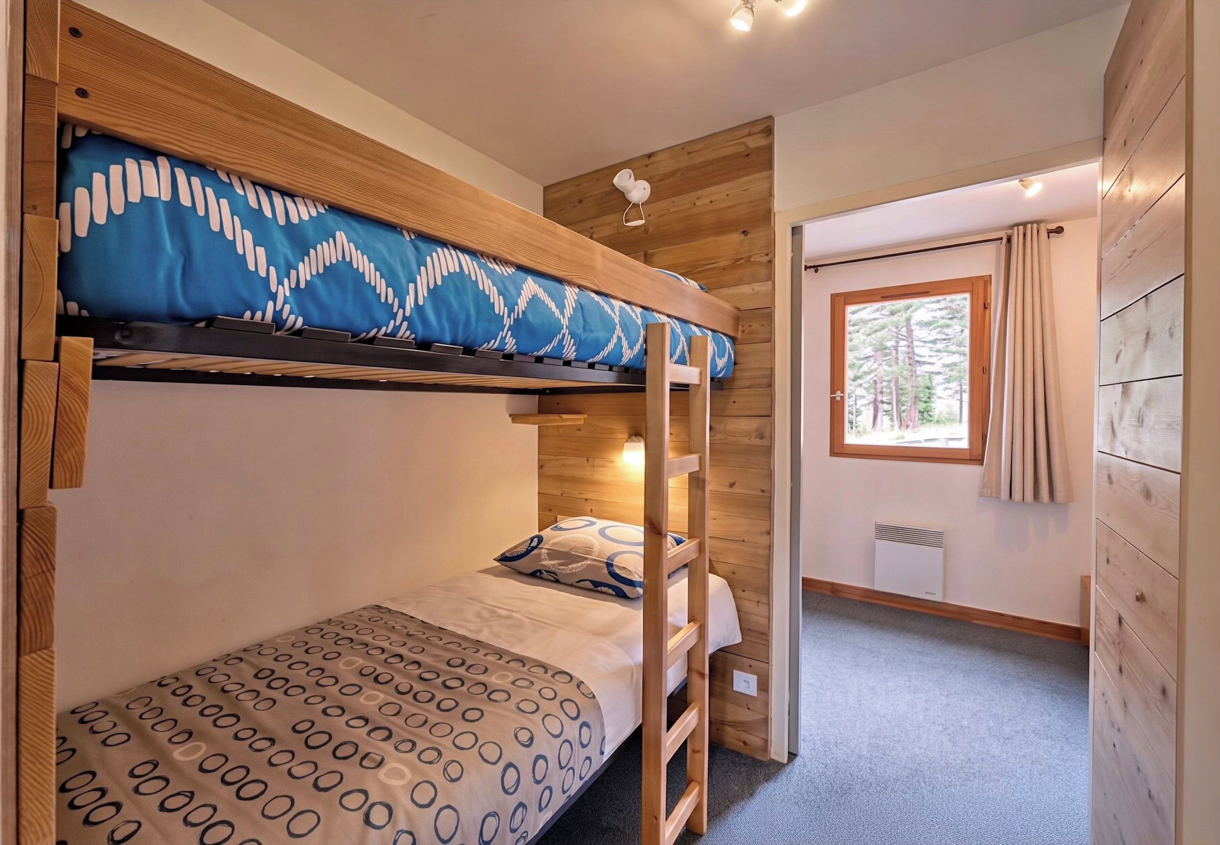 Une chambre avec un lit superposé, une fenêtre et un radiateur.