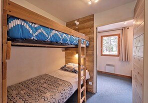 A bunk bed room with a window and a radiator.