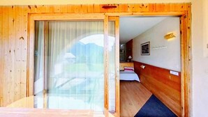 A wooden-framed room with a sliding glass door leading to a balcony. - CASA-Joubarbe Super 4p terrasse plein sud Arvieux! (Arvieux)