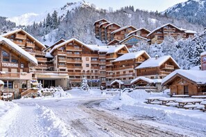 A snow-covered lodge with multiple wooden buildings, a central entrance, and a dirt road leading through the property.