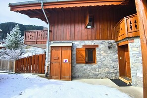 A wooden building with a stone facade, a wooden balcony, and a snow-covered ground. - CASA-Chalet du Merle 1 : Refuge alpin à Champagny (Champagny-en-Vanoise)