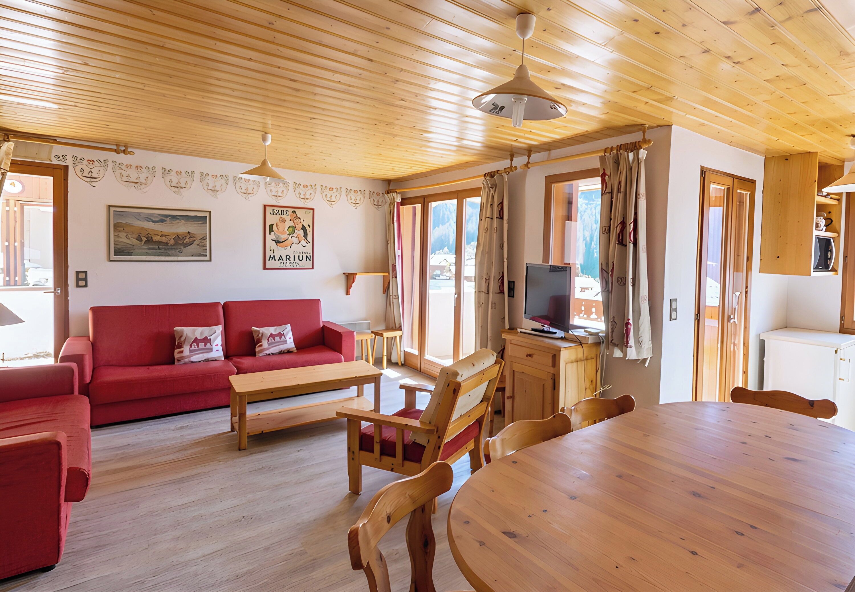 A wooden ceiling, a red sofa, a wooden dining table, and a television.