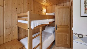 Habitación con literas de madera, una puerta y una lámpara fijada a la pared.