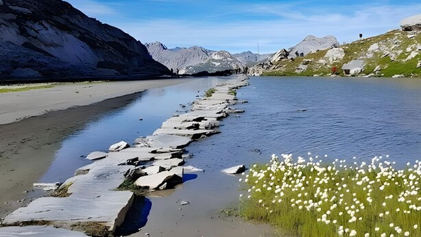 Une rivière paisible, aux rives rocheuses, avec des montagnes en arrière-plan.
