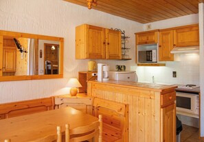 Una cocina de madera con una mesa de comedor y sillas, un microondas y una estufa.