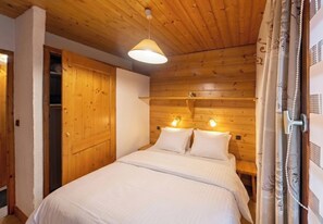Ein Schlafzimmer mit einem hölzernen Kopfteil, einem Bett mit weißer Bettwäsche und einer hängenden Leuchte.