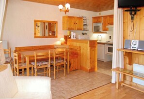 A cozy kitchen with wooden cabinets, a dining table with chairs, and a small island with a sink.