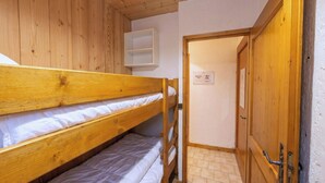 Ein Schlafraum mit Etagenbett, Holztür und weißer Wand.
