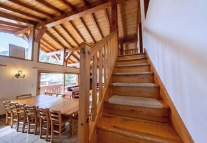 Un escalier en bois offrant une vue sur un coin repas et sur le paysage extérieur.