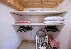 A neatly organized storage area with shelves, a hanging rack, and a baby crib. - CASA-Chalet du Merle 2 à Champagny-en-Vanoise (Champagny-en-Vanoise)