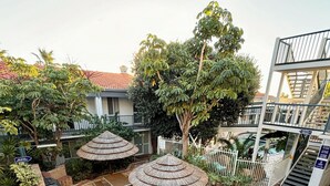 A courtyard with thatched umbrellas, a brick pathway, and a small seating area. - Coastal Beach Retreat Scarborough Pool & Slide! (Scarborough)