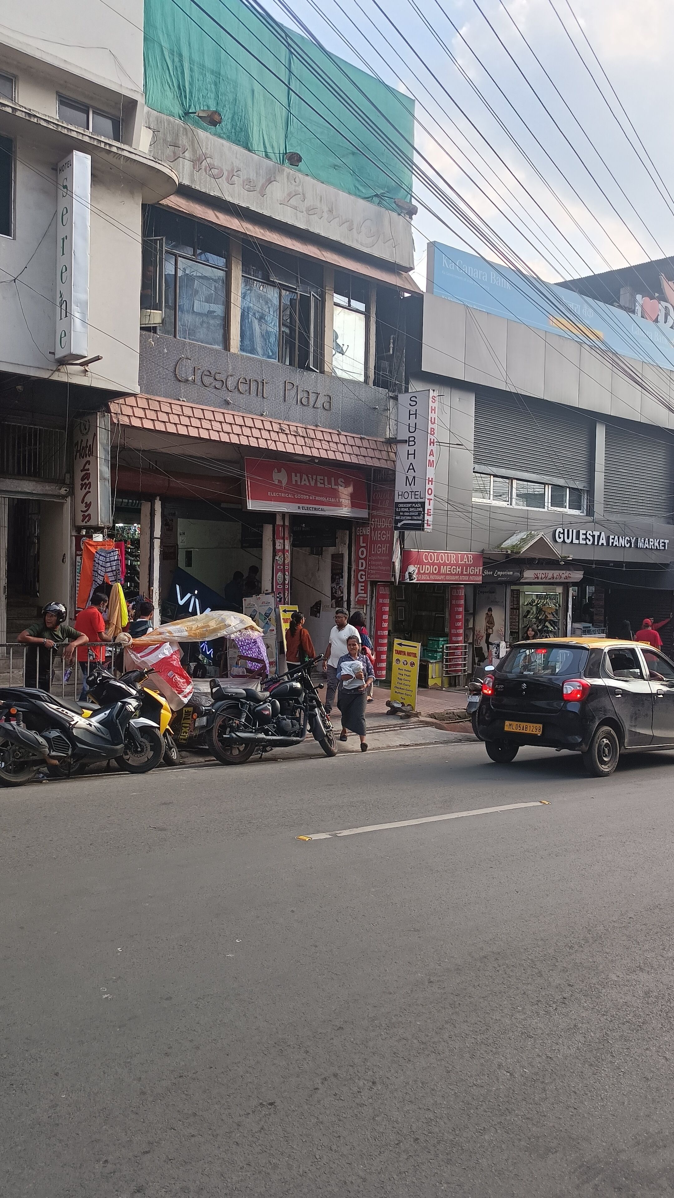 Una vista di una strada con l'hotel 'Hotel Shubham' e il mercato 'Gulesta Fancy Market' in evidenza.