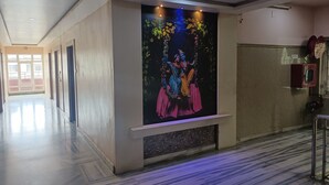 Un pasillo con piso de mármol, un mural grande en la pared y una puerta con picaporte rojo.