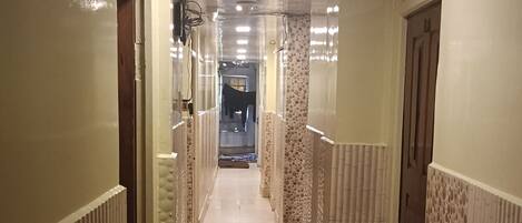 A hallway with patterned walls and a tiled floor, leading to a room with a door at the end.