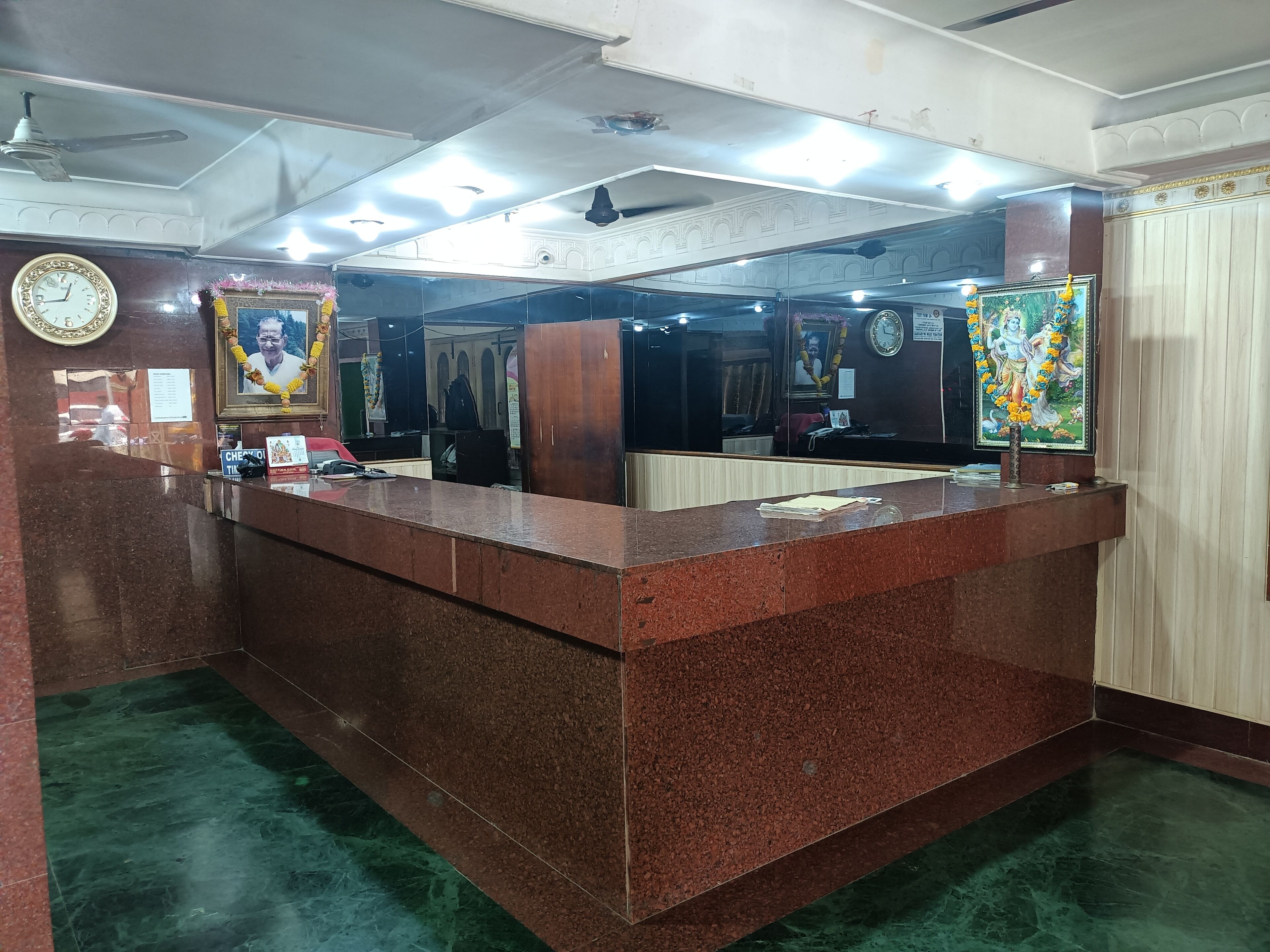 A reception desk with a marble counter, a clock, and a framed portrait.