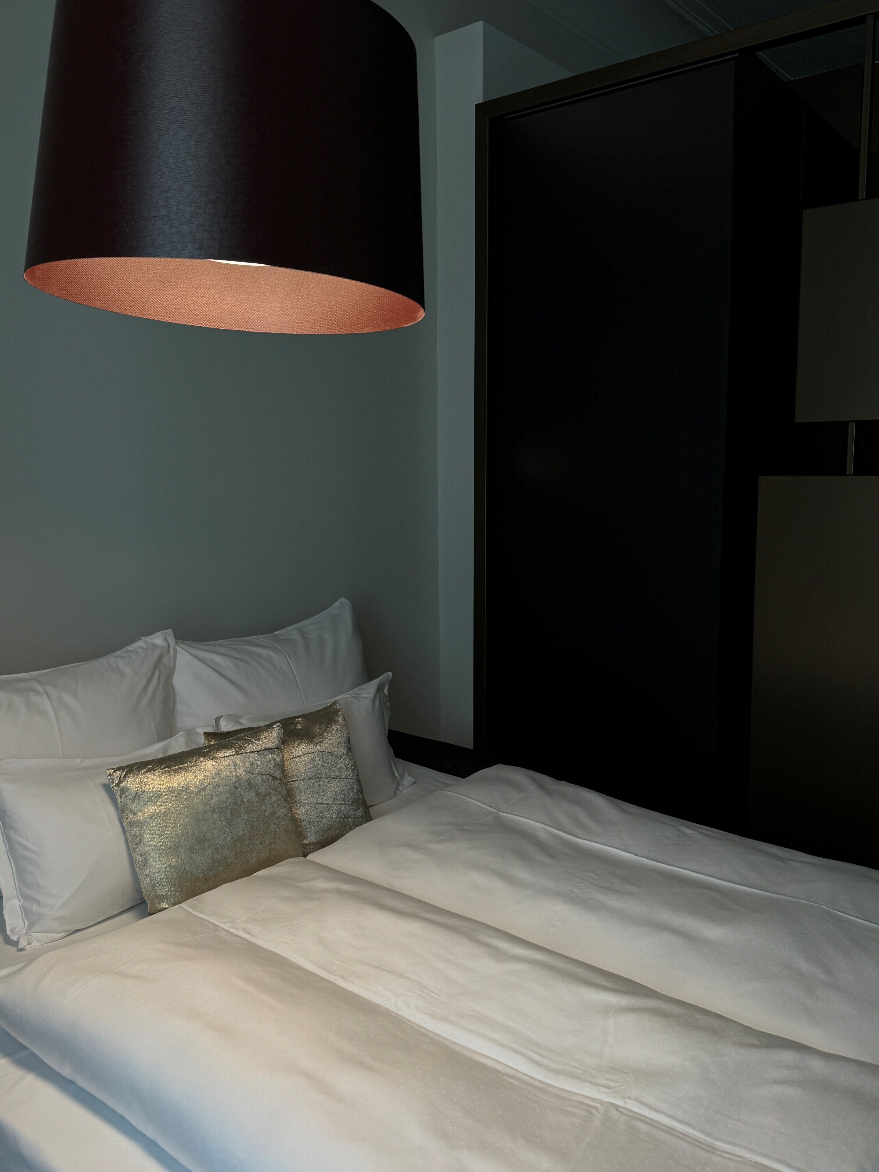 Un lit bien fait, avec du linge de lit blanc et un seul coussin décoratif.
