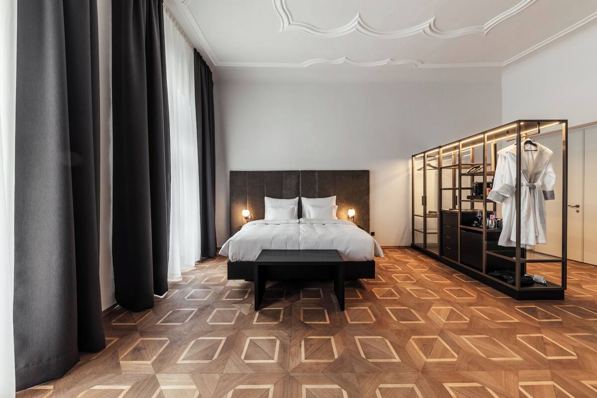 A hotel room with a large bed, a wardrobe, and a bench.