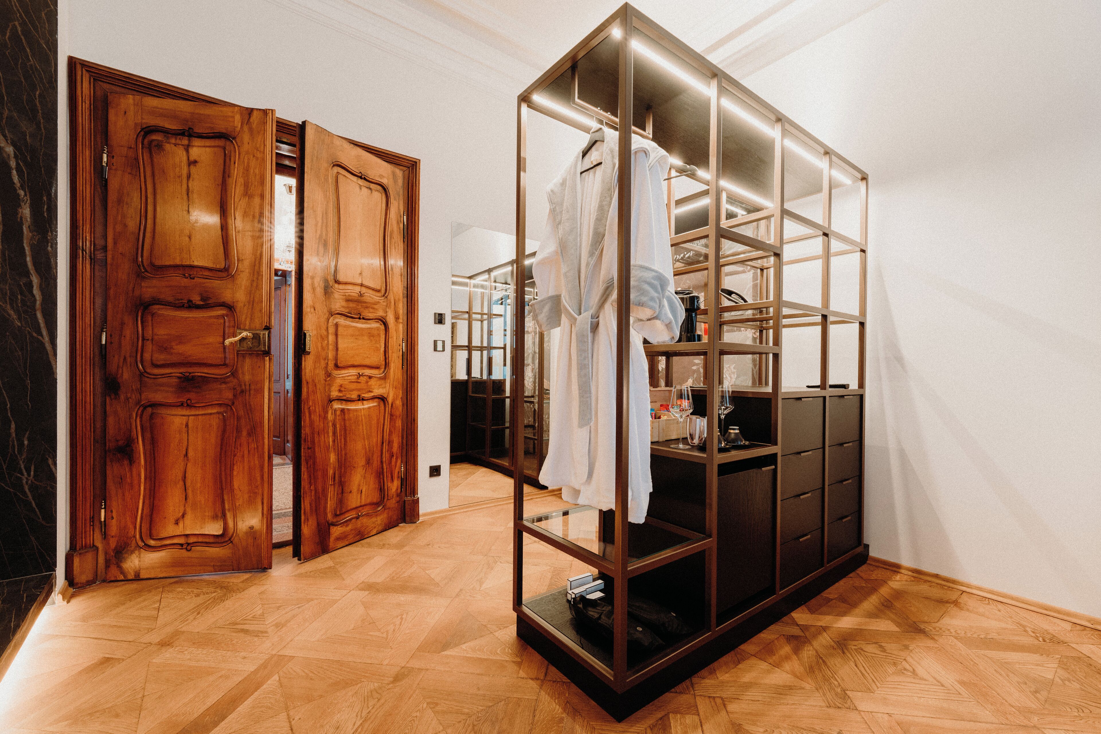 A room with a wooden door, a glass-fronted wardrobe, and a herringbone-patterned floor.