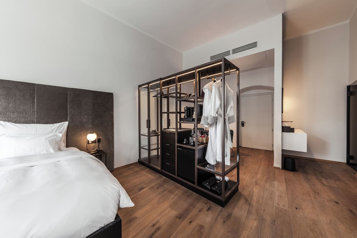 A modern hotel room with a bed, a wardrobe, and a desk area.