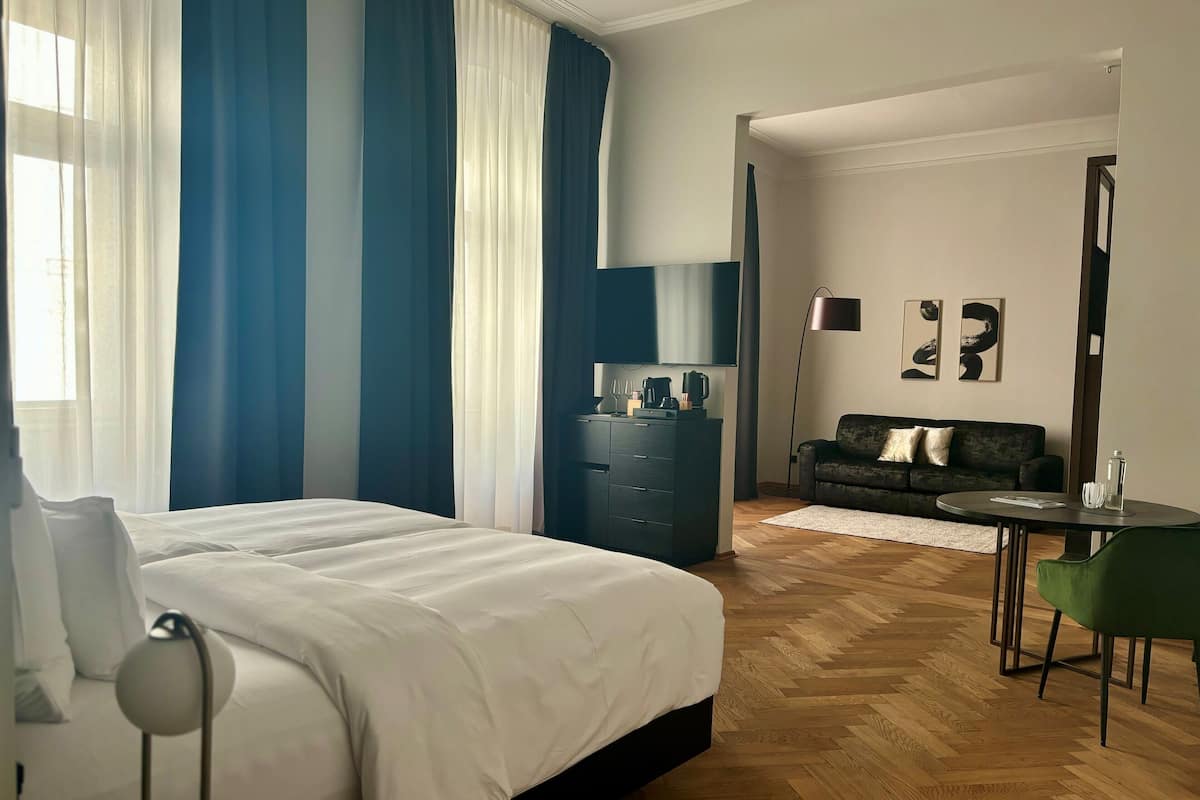 A hotel room with a large bed, a dresser, a desk with a lamp, a sofa, and a coffee table.