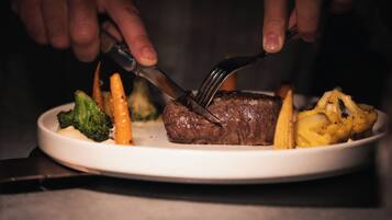 Une assiette contenant un steak, des brocolis, des carottes et un épi de maïs.