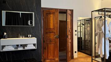 Een moderne badkamer met een marmeren wastafelmeubel, een houten deur en een inloopkast met een glazen deur.