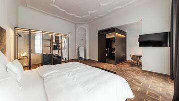 A hotel room with a large bed, a walk-in closet, a bathroom, and a TV mounted on the wall.