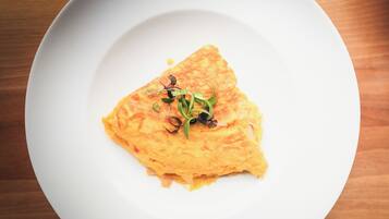 A white plate with a slice of omelette garnished with microgreens.