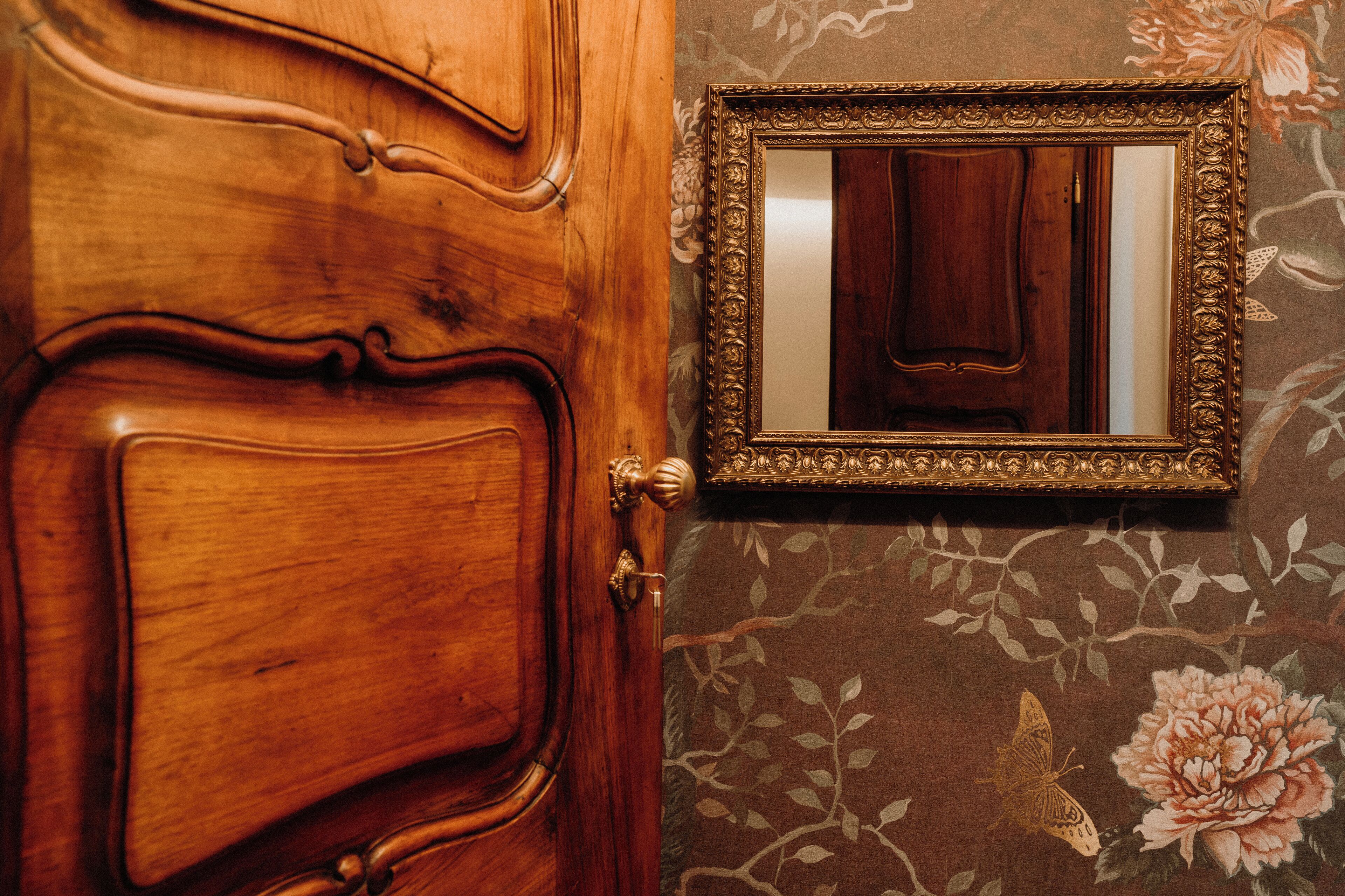 A wooden door with an ornate design and a gold-framed mirror.