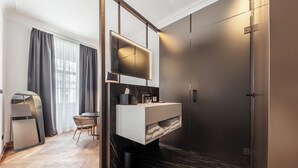 Un bagno moderno con pavimento in marmo, lavabo incassato, specchio e box doccia dai toni scuri.