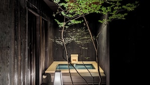 A spa area with a wooden bath, a stone bench, and a small wooden structure. - ROJIYU KYOTO (Kyoto)