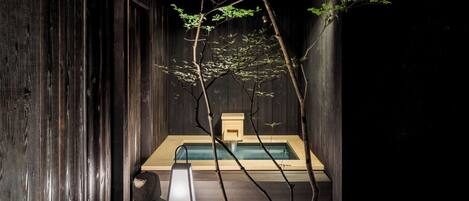 A spa area with a wooden bath, a stone bench, and a small wooden structure.