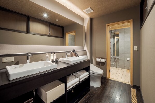 Un baño moderno con dos lavamanos, un inodoro y una zona de ducha.