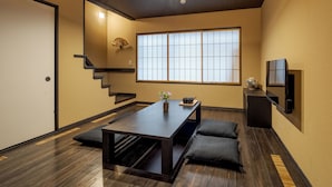 A modern interior with a wooden floor, a dark table, and two cushions. - ROJIYU KYOTO (Kyoto)