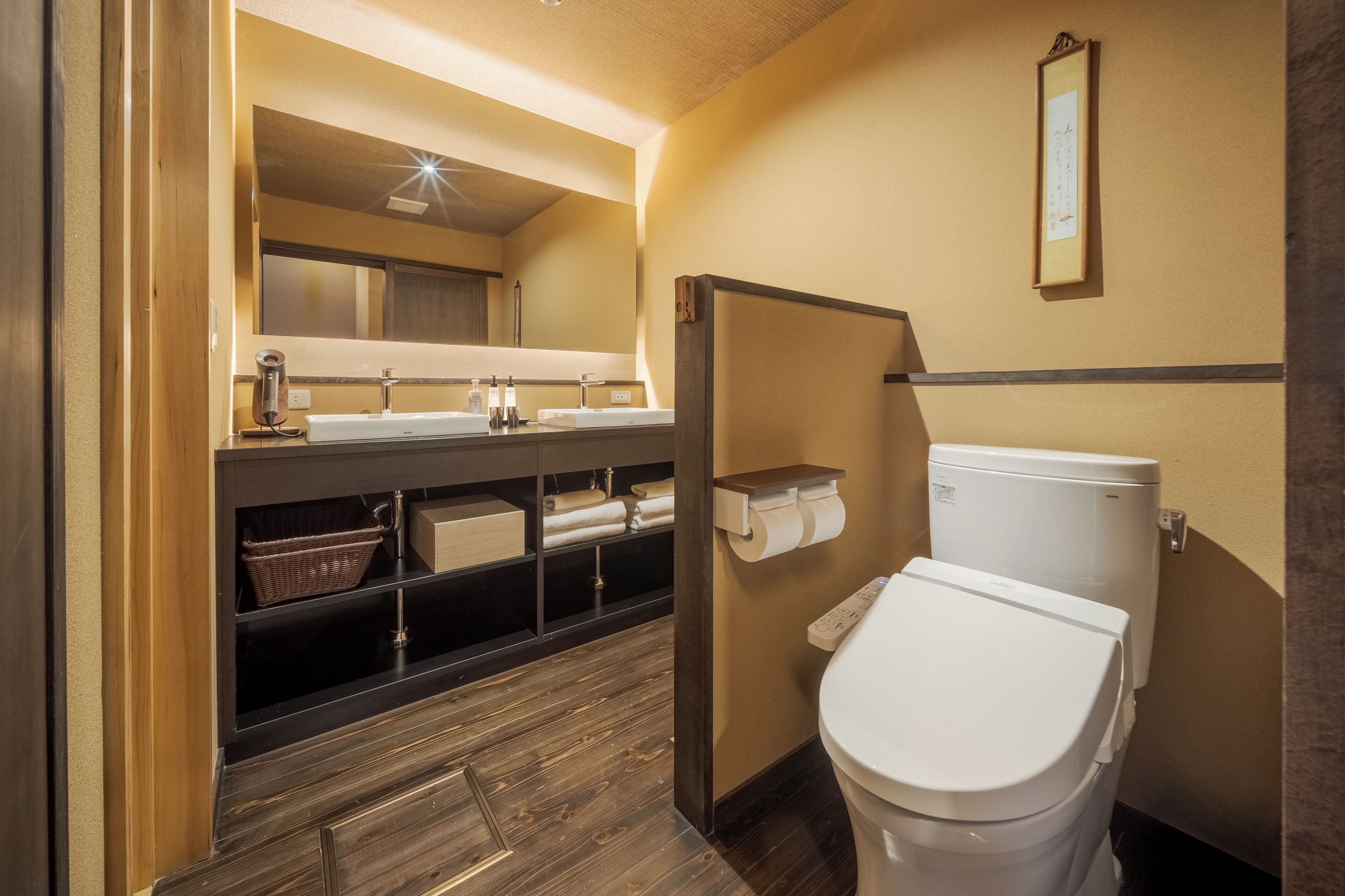 A compact bathroom with a wooden vanity, a toilet, and a shelf with towels.