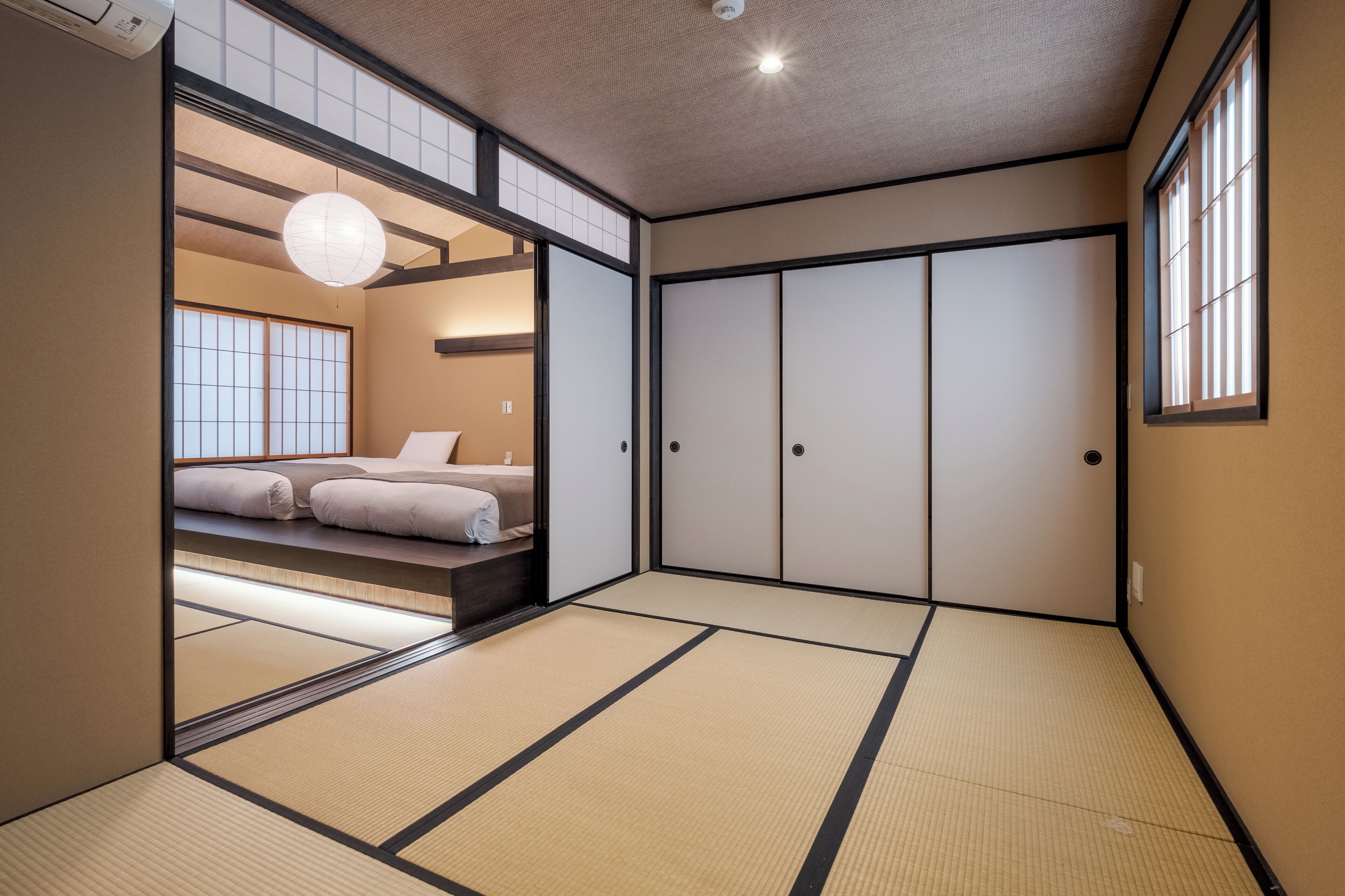 A traditional Japanese-style room with tatami flooring, sliding doors, and a bed with a futon.