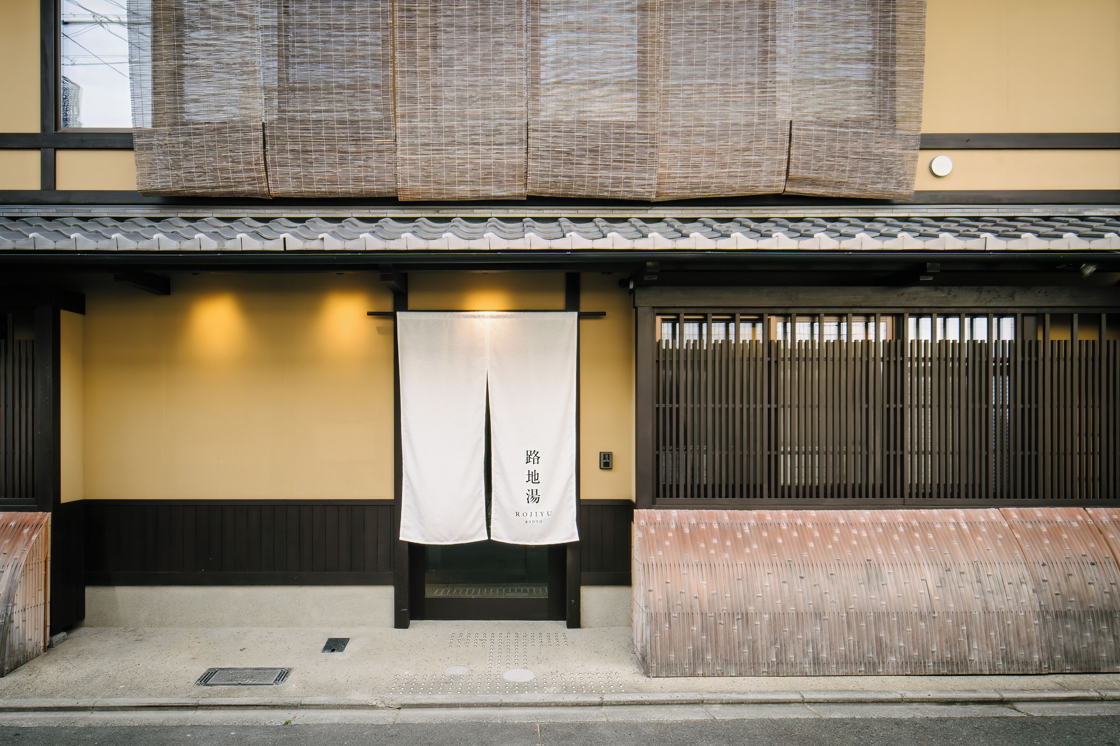 A traditional Japanese building with a tiled roof, a wooden entrance, and a sign with Japanese characters.