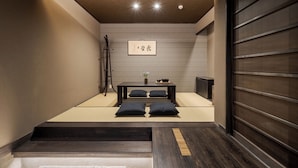 A minimalist room with a bed, a small table with a vase, and a framed picture on the wall. - ROJIYU KYOTO (Kyoto)