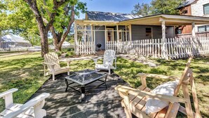 A covered patio area with Adirondack chairs, a fire pit, and a wooden deck.